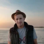 Mężczyzna w kamizelce i kapeluszu na stojący na tle morza