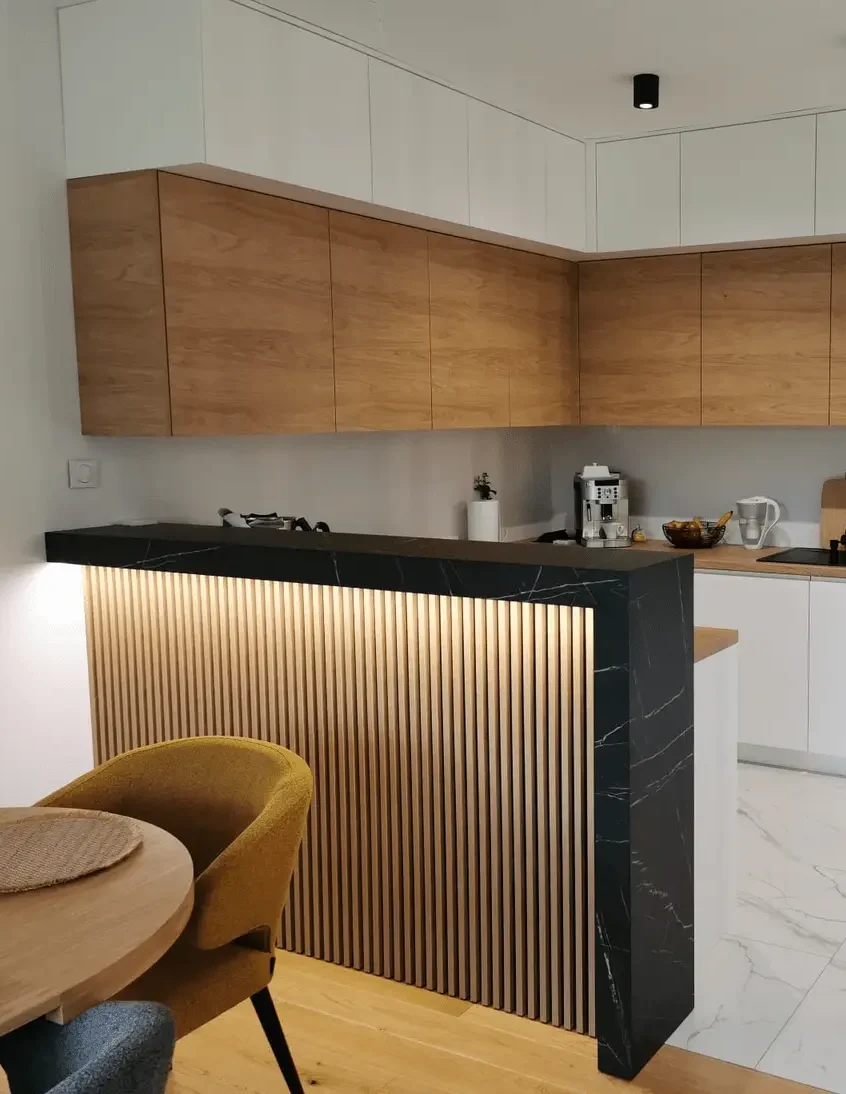 Nowoczesna podświetlana zabudowa kuchenna w jasnych kolorach połączonych z drewnem